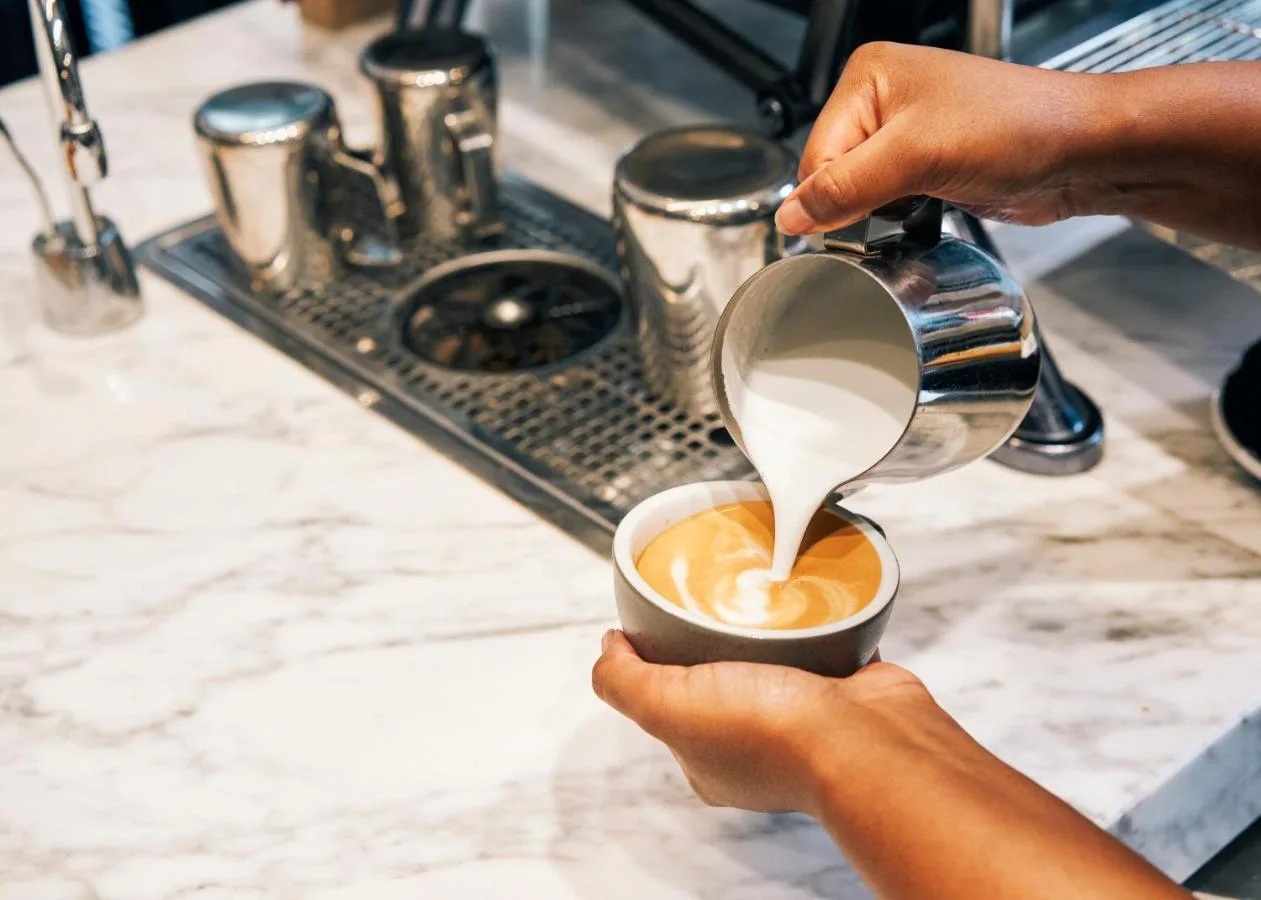 a person pouring milk into a cup of coffee at Page8, Page Hotels in London