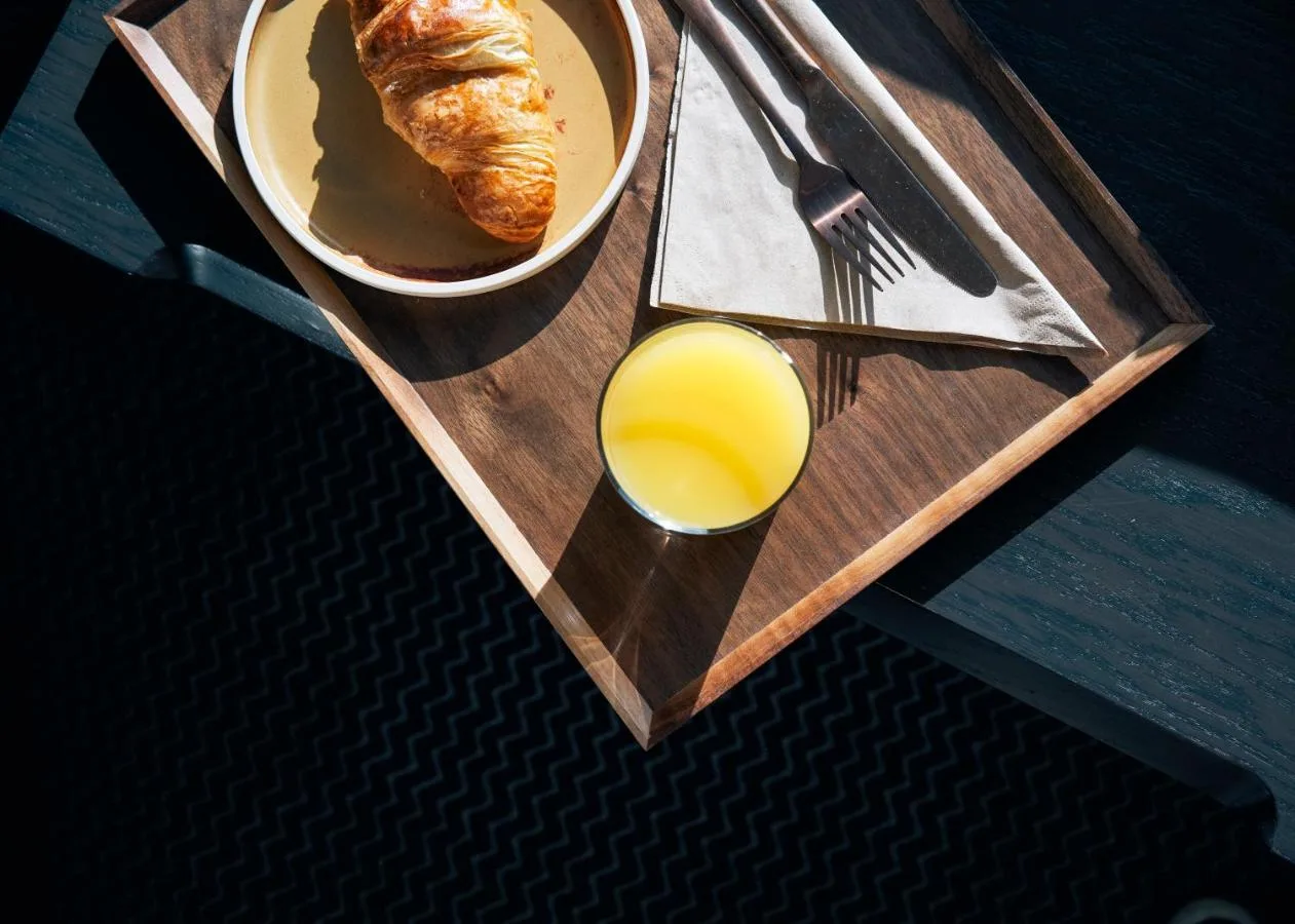 a wooden tray with a glass of orange juice and a bowl of bread at Page8, Page Hotels in London
